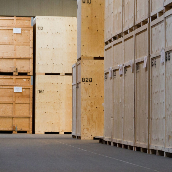 Reihe nummerierter Holzkisten in einem gesicherten Umzugslager zur sicheren Einlagerung von Umzugsgut.