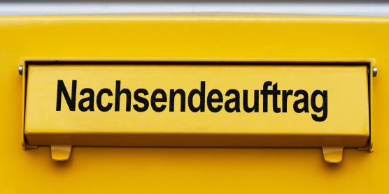 Briefkasten mit gelber Klappe und der Aufschrift „Nachsendeauftrag bei der Post“ für Umzugsservice und Postweiterleitung.