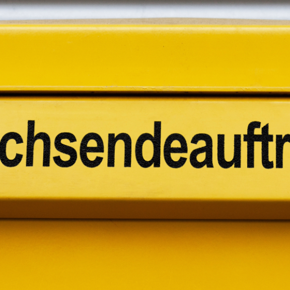 Briefkasten mit gelber Klappe und der Aufschrift „Nachsendeauftrag bei der Post“ für Umzugsservice und Postweiterleitung.