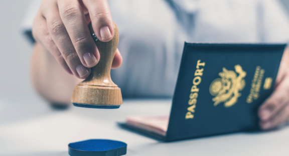 Ein Reisepass wird gestempelt. Symbolisiert die Formalitäten und Einreise-Organisation im Rahmen des Relocation Service für Expats.