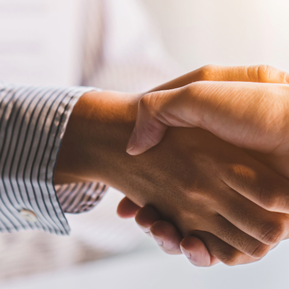 Händeschütteln zweier Personen bei einem Geschäftstreffen oder Jobangebot. Symbol für Einigung und berufliche Chance.