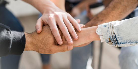 Verschiedene Hände übereinander als Symbol für Zusammenarbeit in unserem Partnernetzwerk.