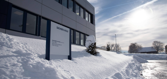 Firmengebäude mit verschneitem Außenbereich beim Umzug im Winter – klarer Himmel und Sonnenlicht im Hintergrund