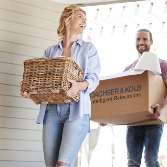 Paar trägt Umzugskartons und Körbe in neues Zuhause – Tipps und Hilfe im Umzugsratgeber