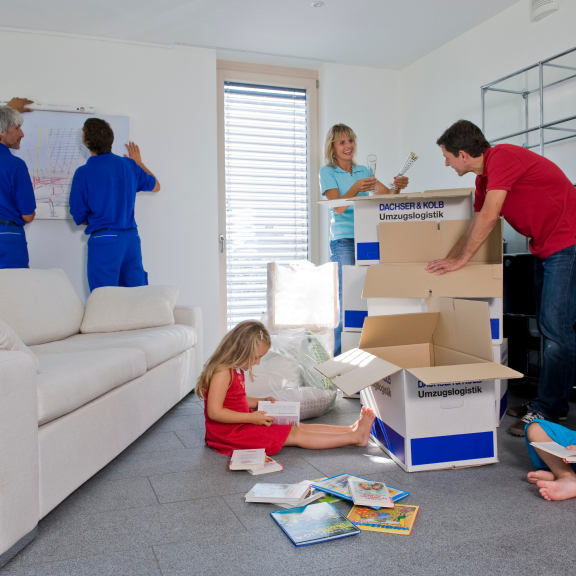 Umzugsdienstleistungen in Aktion: Möbel werden montiert, Kartons ausgepackt und Kinder genießen Bücher im neuen Zuhause.