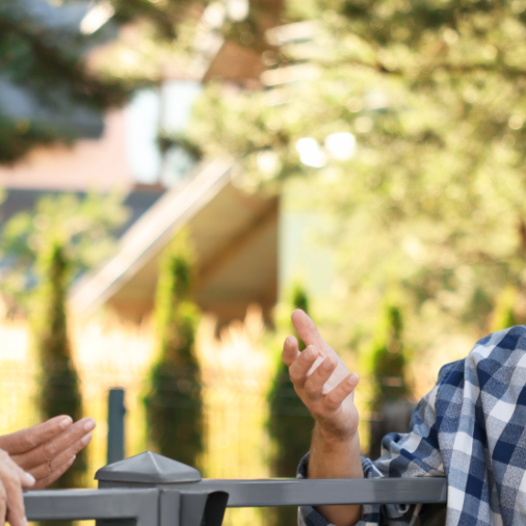 Zwei Paare unterschiedlichen Alters unterhalten sich freundlich im Freien. Nachbarschaft kennenlernen nach dem Umzug.