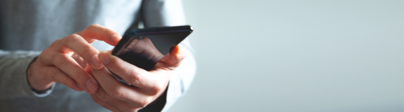 Hände tippen auf ein Smartphone. Recherche zum Nachbarschaft kennenlernen nach dem Umzug.