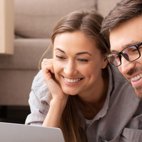 Paar plant den Umzug am Laptop vor Umzugskartons im Wohnzimmer