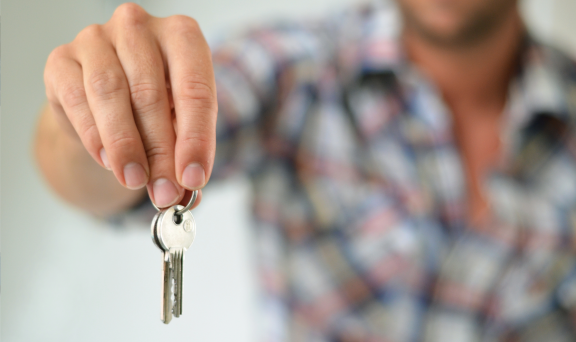 Mann übergibt Wohnungsschlüssel nach Kündigung der Wohnung, Symbol für Wohnungsrückgabe