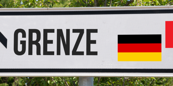 Schild „Grenze“ mit Pfeil sowie deutscher und Schweizer Flagge als Symbol für Zoll Schweiz
