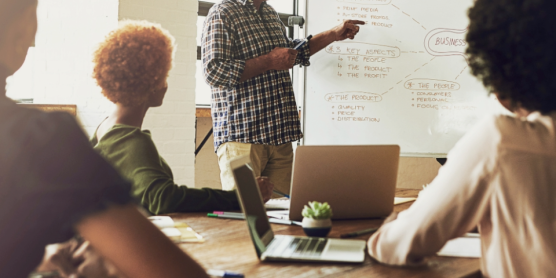 Team bei einer Besprechung mit Whiteboard – Symbolbild für Tipps und Wissen im Umzugs-ABC