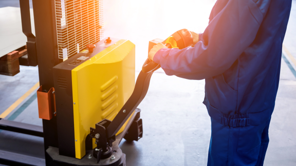 Mitarbeiter bewegt Palette mit Elektrohublifter – Vorbereitung für LCL (Teilcontainerladung) im Lager