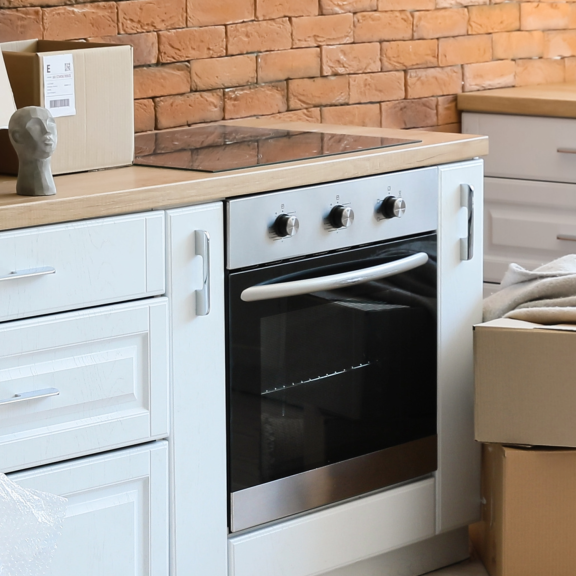 Umzugskartons in einer neuen oder frisch montierten Küche, bereit zum Auspacken. Fokus auf Küchenmontage.