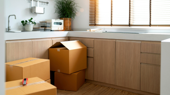 Umzugskartons stehen in einer modernen Küche, bereit für die Küchenmontage. Neuanfang im neuen Zuhause.