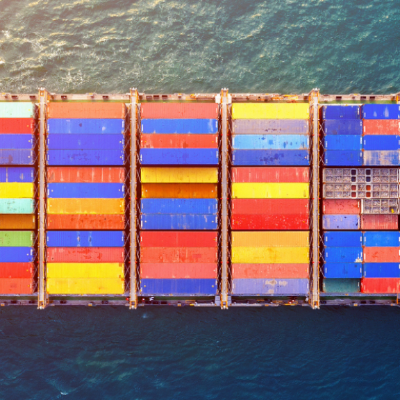 Drohnenaufnahme eines riesigen Frachtschiffs voller bunter Container auf dem Meer. Repräsentiert Full Container Load (FCL).