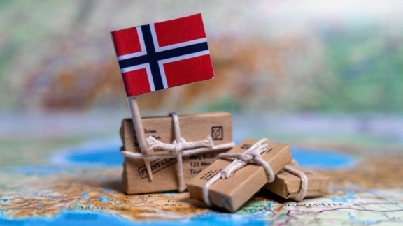 Norwegische Flagge auf kleinen Paketen auf einer Landkarte als Symbolbild für Einreise nach Norwegen