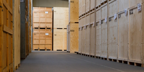 Row of numbered wooden crates in a secured moving warehouse for the safe storage of goods.